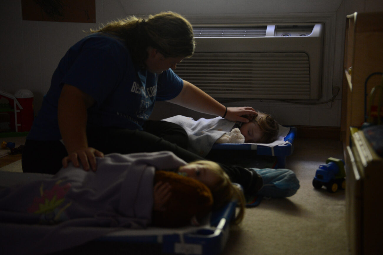 A caretaker at Early Head Start childcare, Kayla Morgan, helps two twins fall asleep for their daily afternoon nap on October 12, 2013 in Hyden, Kentucky.  There are nine children, including one ten-month-old baby, that attend the daycare.