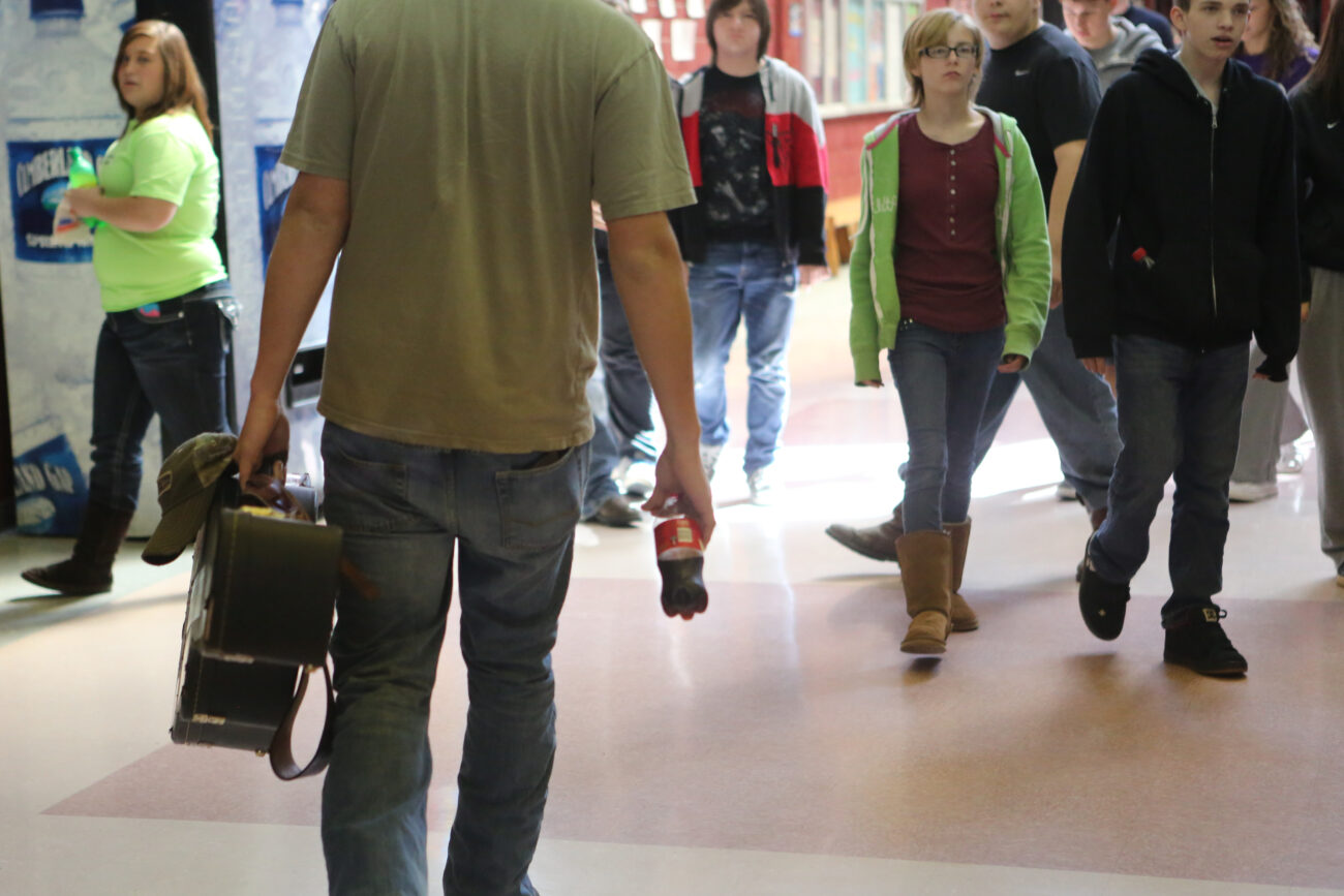 Tanner Horton walks back to class after eating lunch in the office of the vice principal, his dad, at Leslie County High School. Tanner is frequently seen carrying his guitar, hat and a coke. Photo by Emily Wuetcher