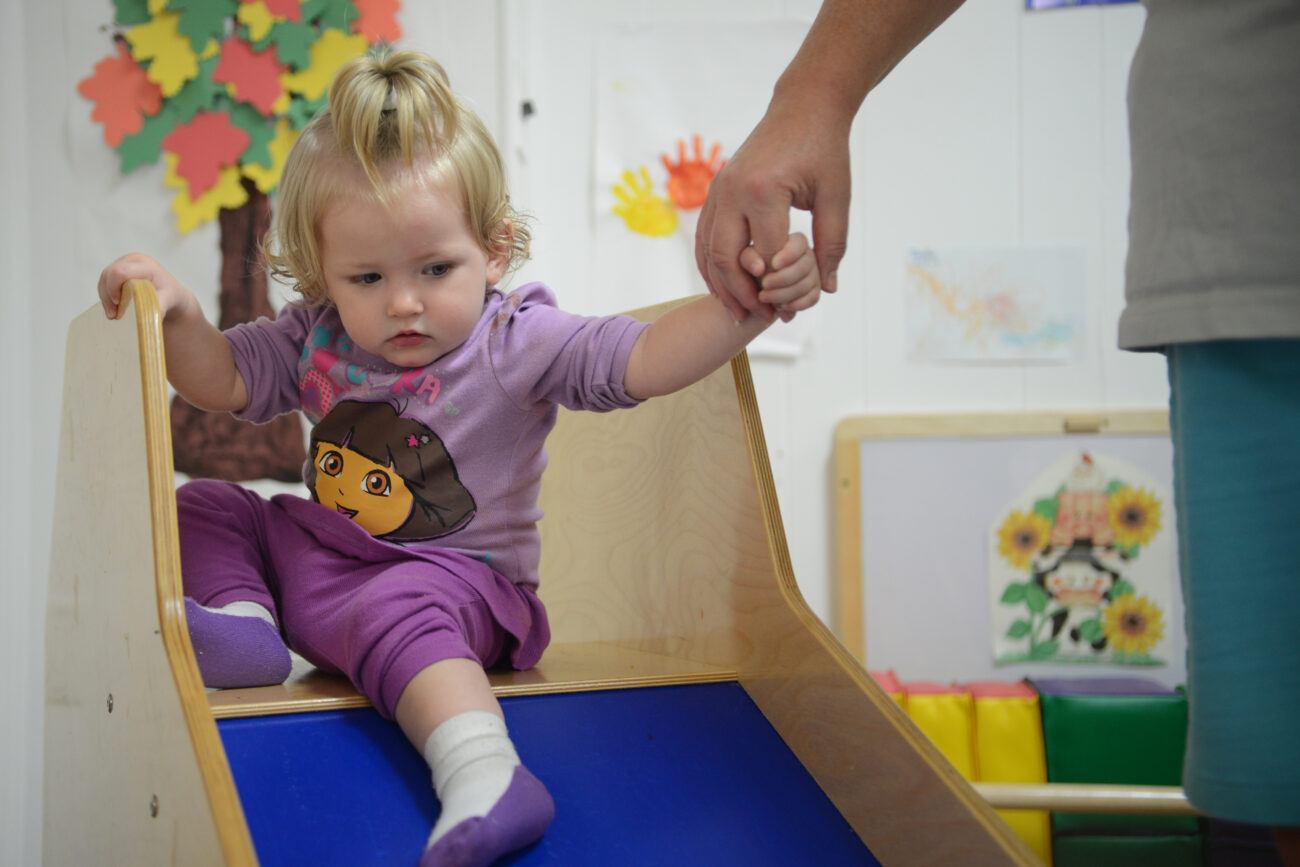At about a year old, Chloe loves going down the slide at Leslie Early Head Start childcare. All the children at Early Start are admitted into the program based on how severe their need is. Chloe lost her mother at 3 months old and is currently being raised by her great aunt.