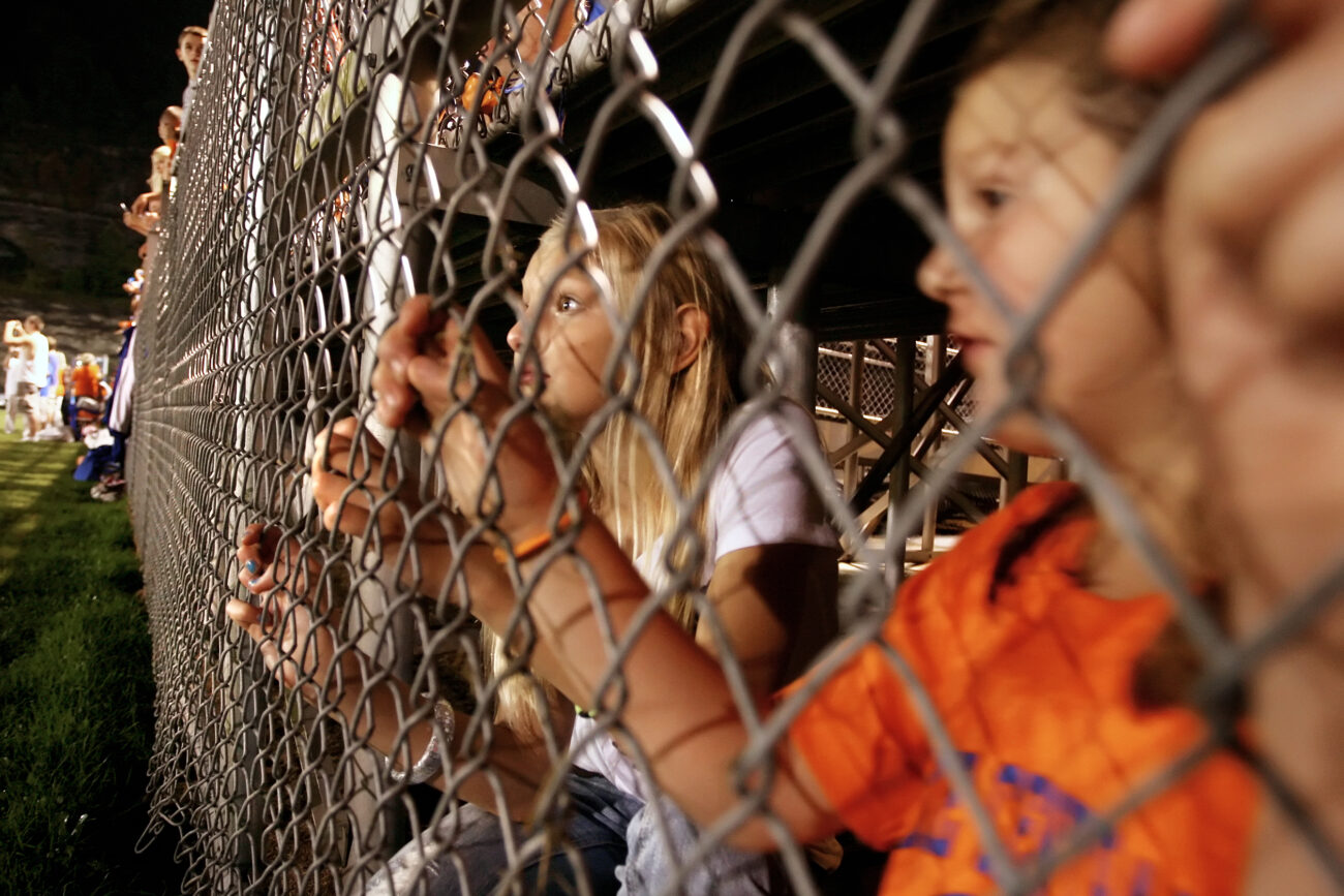 Madison May, 10, and her cousin Makayla May, 6, watch from under the bleachers as Pike County Central High School's 2009 homecoming queen contestants are introduced at the homecoming football game.