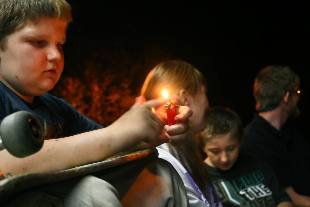William Slone, 11, plays with his lighter next to his mother Masilla Slone, 31, his cousin Johnthan Everage, 11, and mother's friend Anthony Slone, 31, outside the Mi-Dee Mart in downtown Hindman, KY.