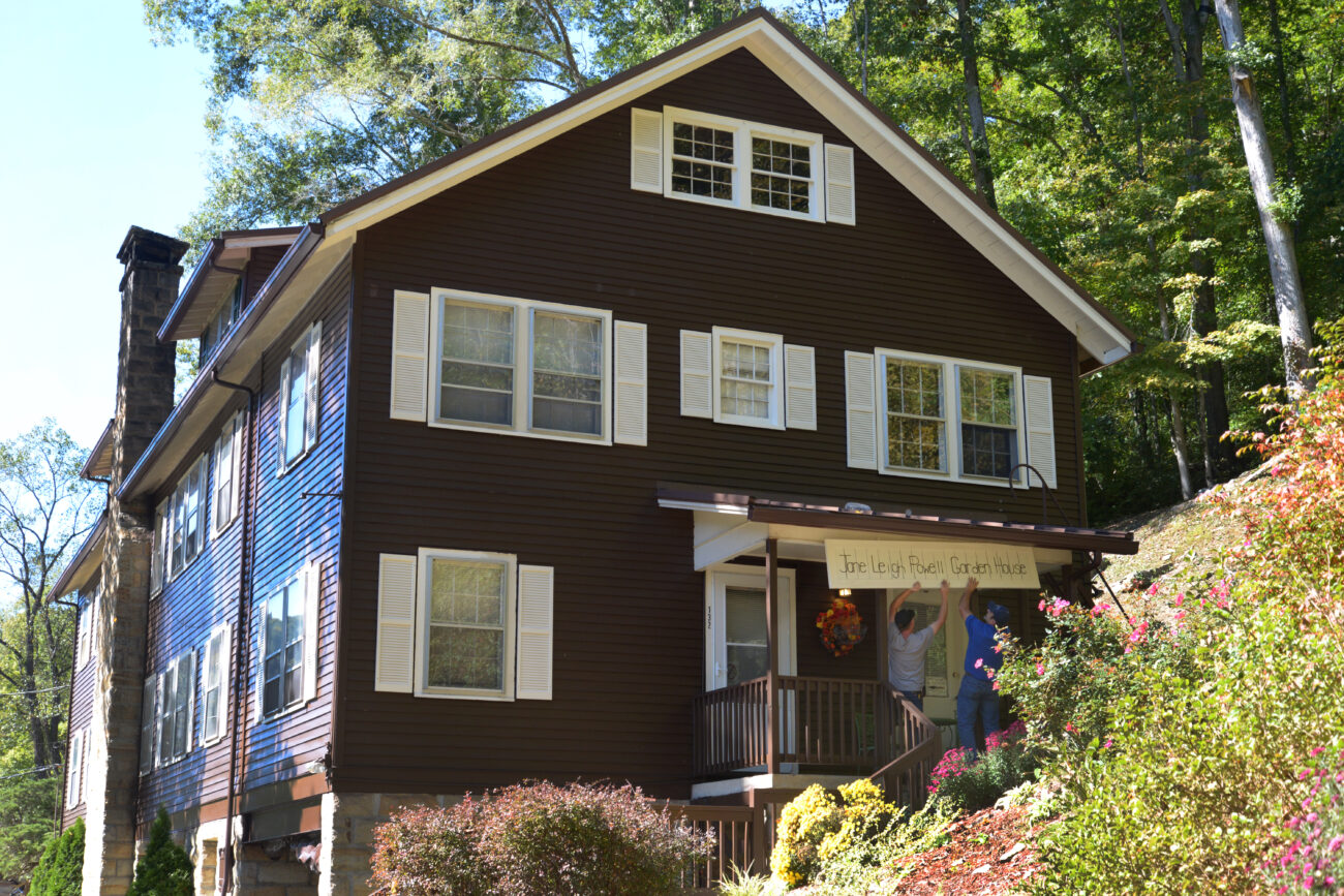 Two of the employees at Frontier Nursing University hang a newly repainted sign above the Jane Leigh Powell Garden House. The Garden House is a place for people visiting the Frontier Nursing University to stay in Hyden, Kentucky, on Wednesday, October 9, 2013. Photo by Eleanor Hasken