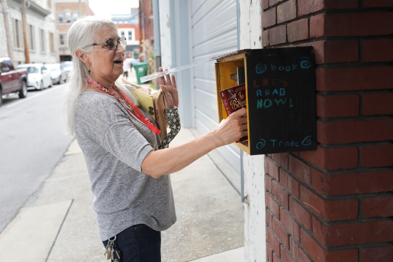 Lizz Taylor checking a take one leave one book box on Lewis Street in Frankfort, Kentucky, on Wednesday, Oct. 13, 2021. Taylor helps keep the box stocked with books.