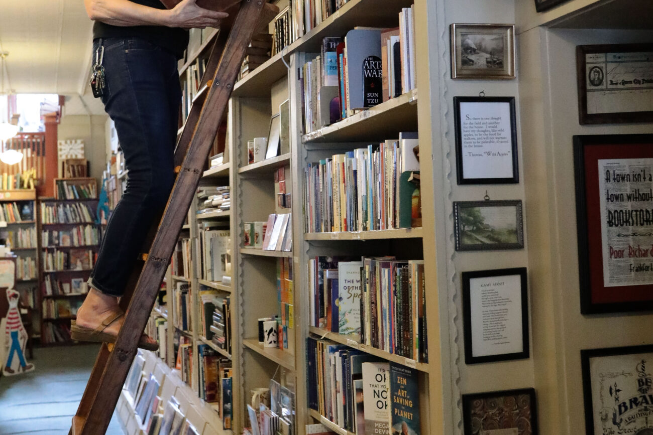 Lizz Taylor climbs up the same ladder she fell from years ago. Where she received a concussion and a few broken ribs. Taylor owns Poor Richard’s Books in Frankfort, Kentucky, on Thursday, Oct. 14, 2021.