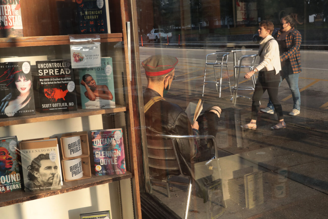 John Rucker, left, reads outside Poor Richard’s Books as customers walk toward the Kentucky Coffee Tree in Frankfort, Kentucky, on Thursday, Oct. 14, 2021. The coffee shop adjoins the book store.