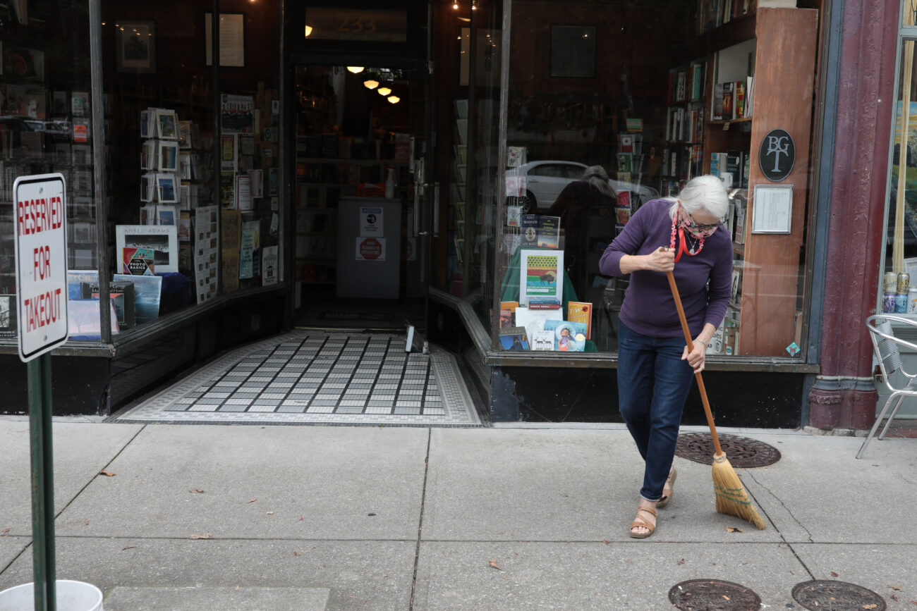 Lizz Taylor, owner of Poor Richard’s Books in Frankfort, Kentucky, sweeps the sidewalk in front of her business Friday, Oct. 15, 2021.