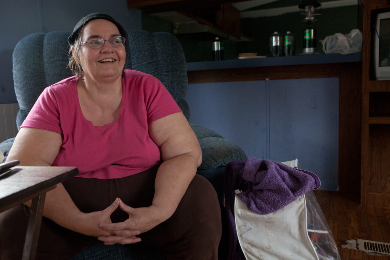 Donna Hall sits in her family's new trailer after being homeless and living in a tent for three weeks. Donna is pursuing a master's degree in creative writing and considers her family blessed to have weathered the difficulties they faced. She plans to write a book about their struggles.