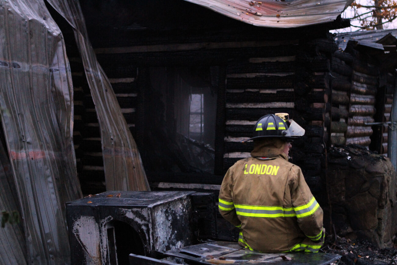 19-year-old Joey Robinson takes a break from fighting a rekindled fire to survey damage to the structure. Photo by Alex Holt