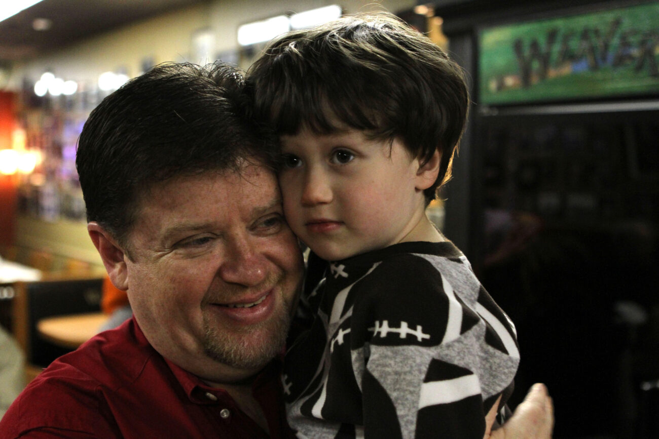 Juddy Weaver, 3rd generation owner of Weaver's Hot Dogs, holds his son Tyson Weaver, the future owner. Photo by Alex Holt