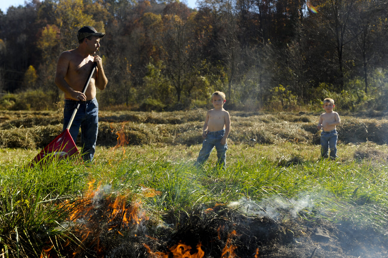 Johnny Bowling burns out dry grass in a ditch by his driveway with his sons Nate, 4, and Nick (right), 2, at their home on Pistol Creek Road. near London, Ky. Burning the brush helps prevent snakes and cleans the area for the upcoming winter.