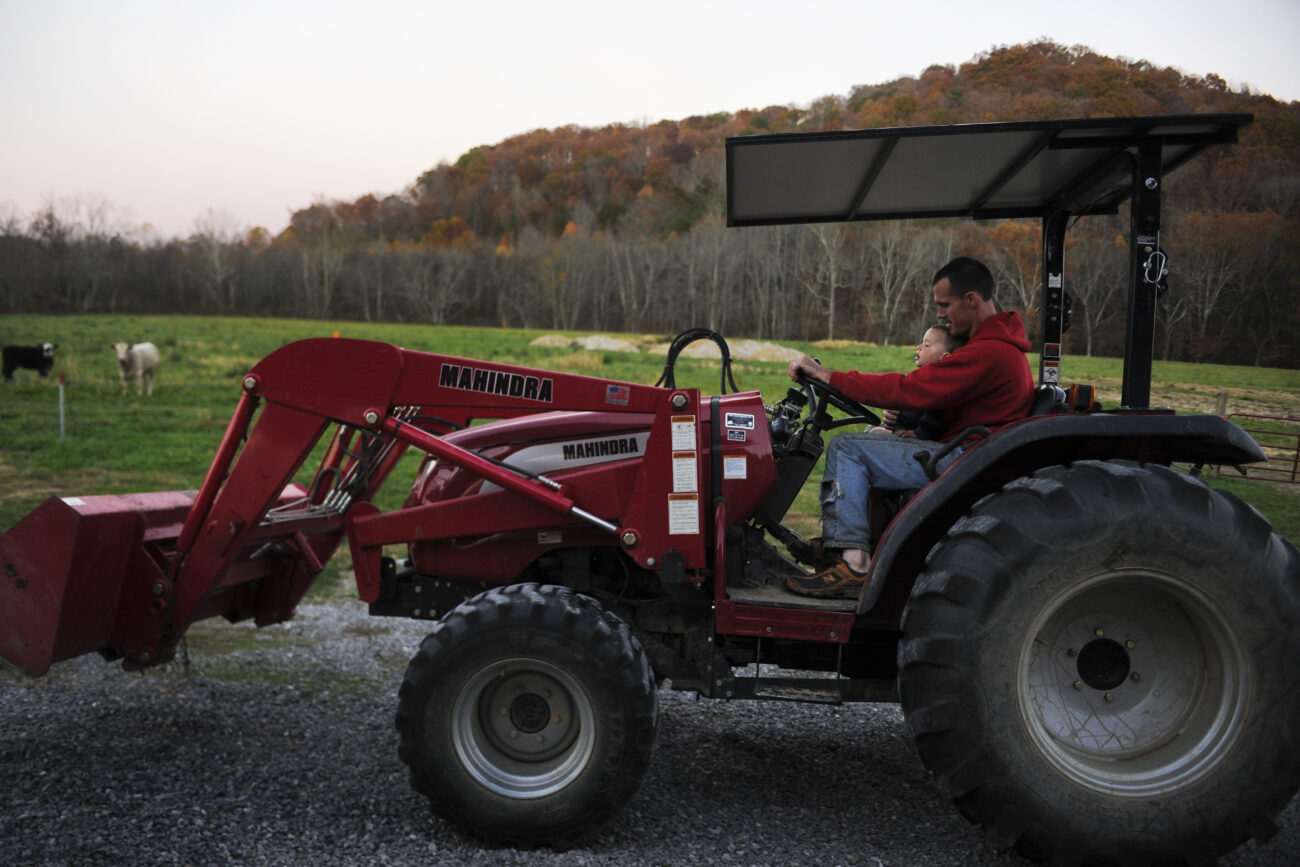 Ford Waterstrat takes his son Finley, 2, for a ride on the tractor as he parks it near the barn for the night. Waterstrat and his wife Amanda said they want to teach Finley as much as they can about the labor and values of farm life.