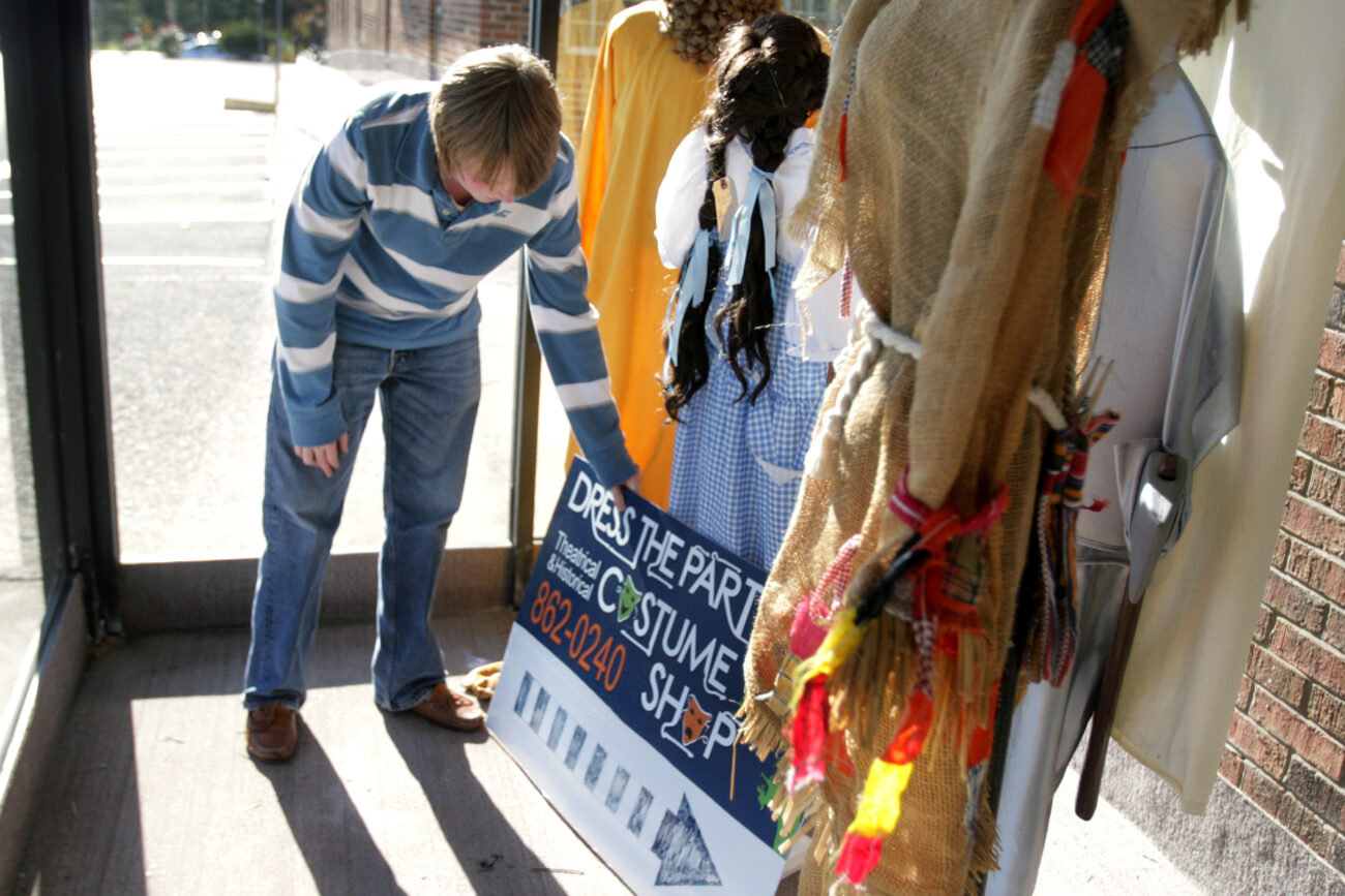 Intern Jonathon Hibbard adjusts a sign in the window display at "Dress the Part Costume Shop" in London, Ky. on Thursday, Oct. 25, 2012. Part of Hibbard's job is keeping the displays in top shape, along with designing costumes and assisting customers. ..Photo by Amelia Orwick