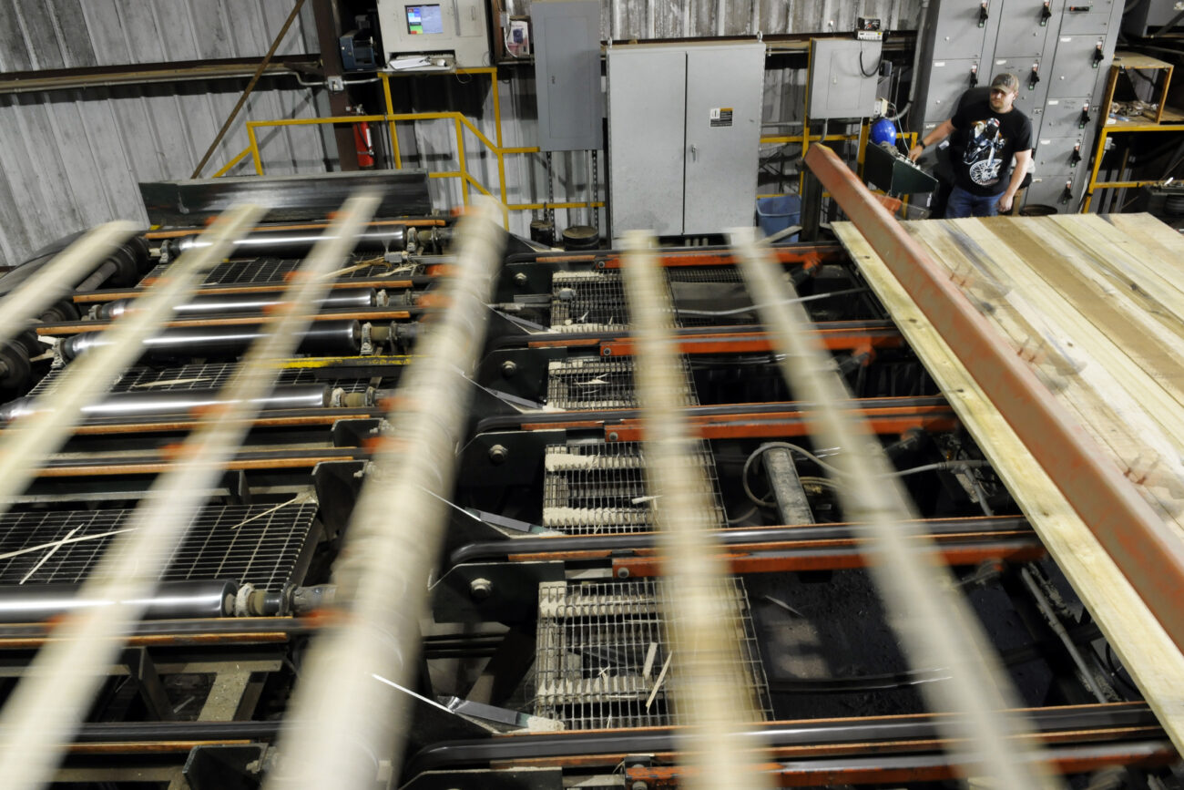 Lumber passes through the stacker machine at Begley Lumber Thursday afternoon. This piece of machinery creates stacks of "green" wood for workers to lay sticks on so the wood dries properly.