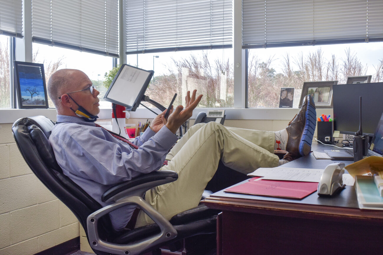 Principal Chris Tracy kicks back at his desk while talking to the football coach at Franklin County High School in Frankfort, Kentucky, on Thursday, Oct. 14, 2021.