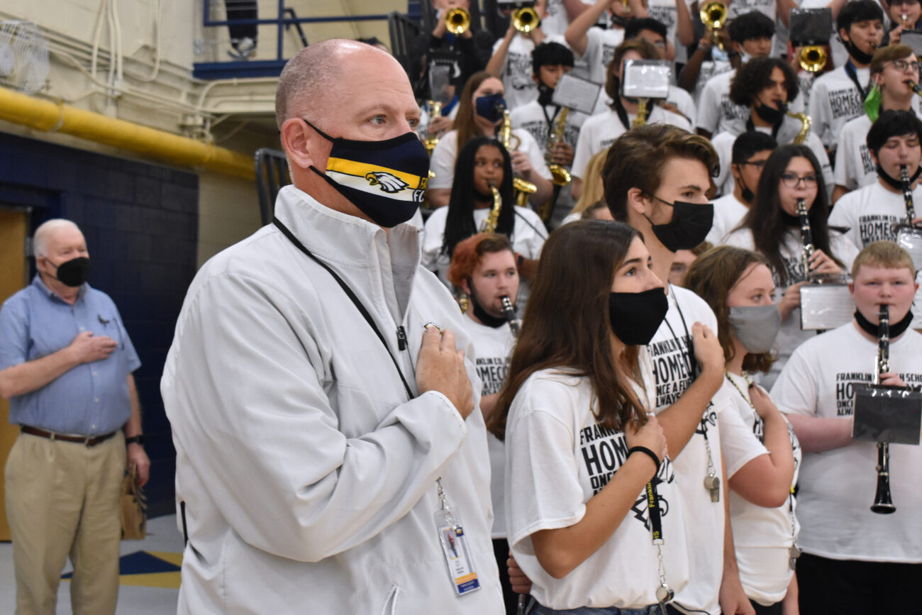 At a homecoming pep rally, Principal Chris Tracy stands for the National Anthem with the student body at Franklin County High School in Frankfort, Kentucky, on Friday, Oct. 15, 2021.