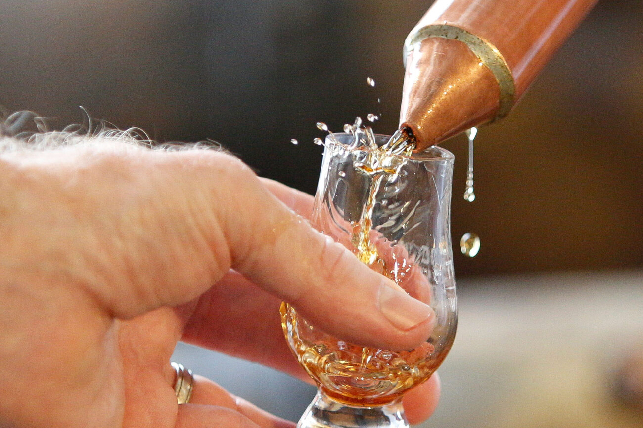 Bourbon splashes out of a glass while a sample is poured from a bourbon thief on Thursday, Oct. 14, 2021, at Three Boys Farm Distillery in Franklin County, Kentucky. Photo by Jack Weaver