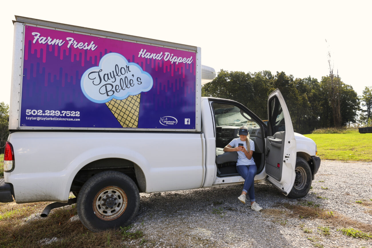 Cook sits on the steps of one of her ice cream trucks while checking her phone on Thursday, Oct. 14, 2021, in Frankfort, Kentucky.