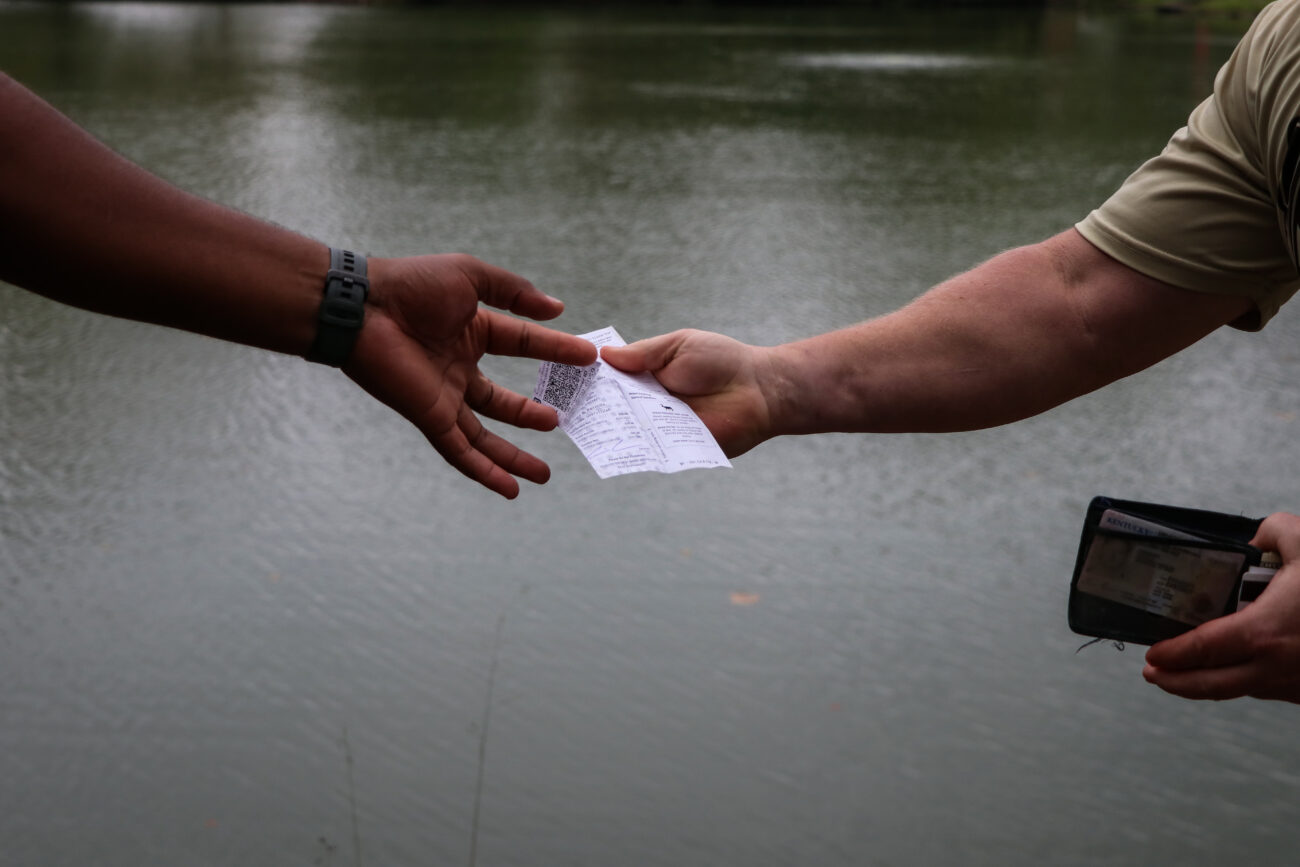 James Brace, left, takes a fishing license from fisherman Kevin Brammer, right, at the Kentucky Department of Fish & Wildlife Resources headquarters on Friday, Oct. 15, 2021, in Frankfort, Kentucky. As a game warden, Brace checks fishing and hunting licenses to make sure sportsmen are in compliance with Fish & Wildlife regulations.