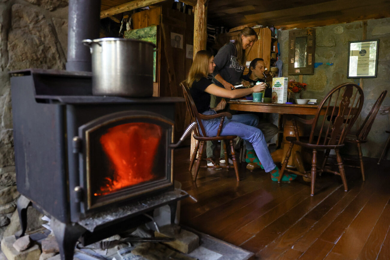Chris Schimmoeller prepares a meal with her family at their kitchen table on Saturday, Oct. 16, 2021, at her home off of Mount Vernon Road in Frankfort, Kentucky. They began building their home, which has no electricity or running water, in 1998 after getting married in 1997. They finished the home in 2002. Photo by Jack Weaver