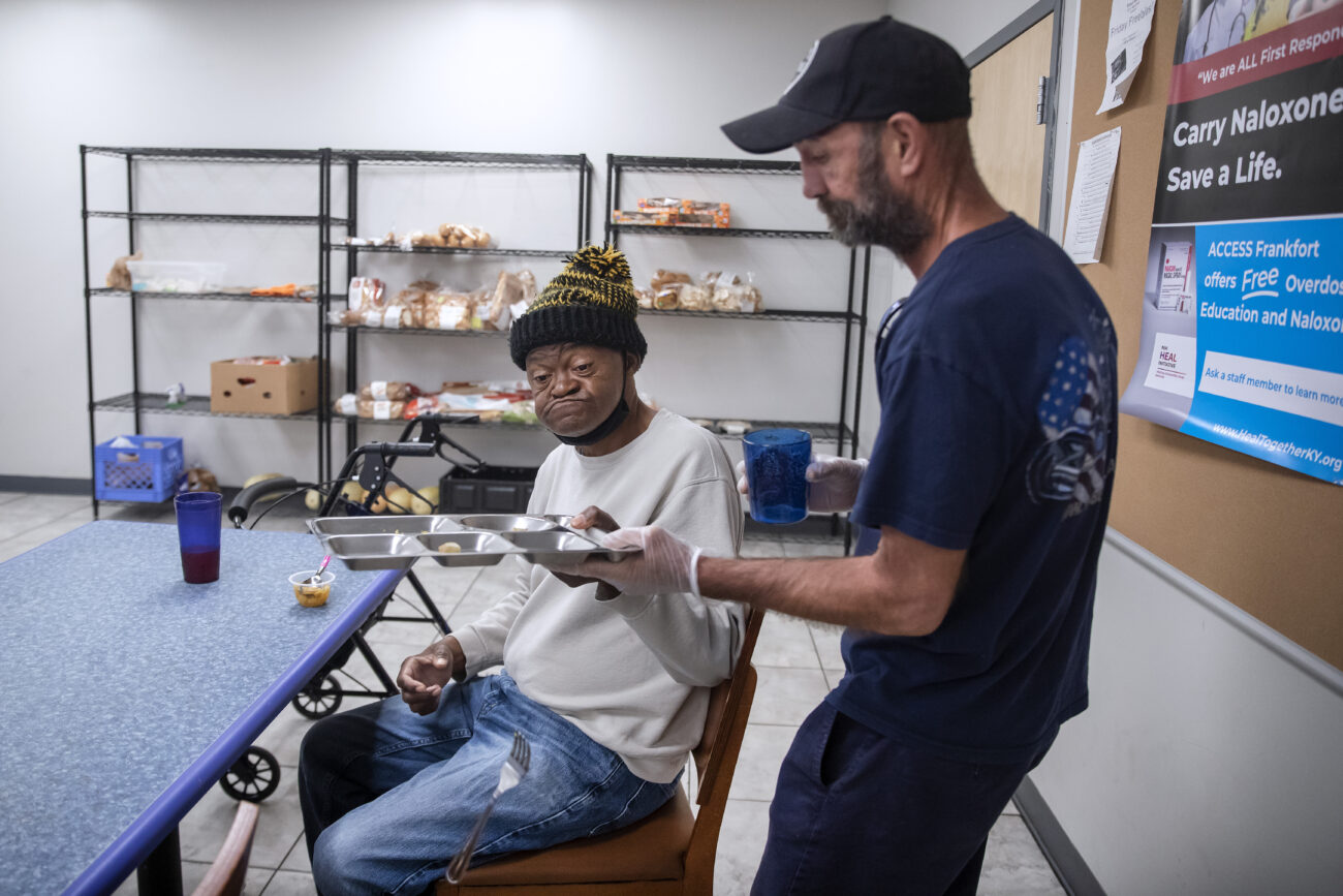 Bobby Davis, a resident at ACCESS, takes a plate from Bruce Clay after lunchtime on Thursday, Oct. 7, 2022 in Frankfort, Kentucky. Most of the residents are employed full-time and volunteer at the shelter.