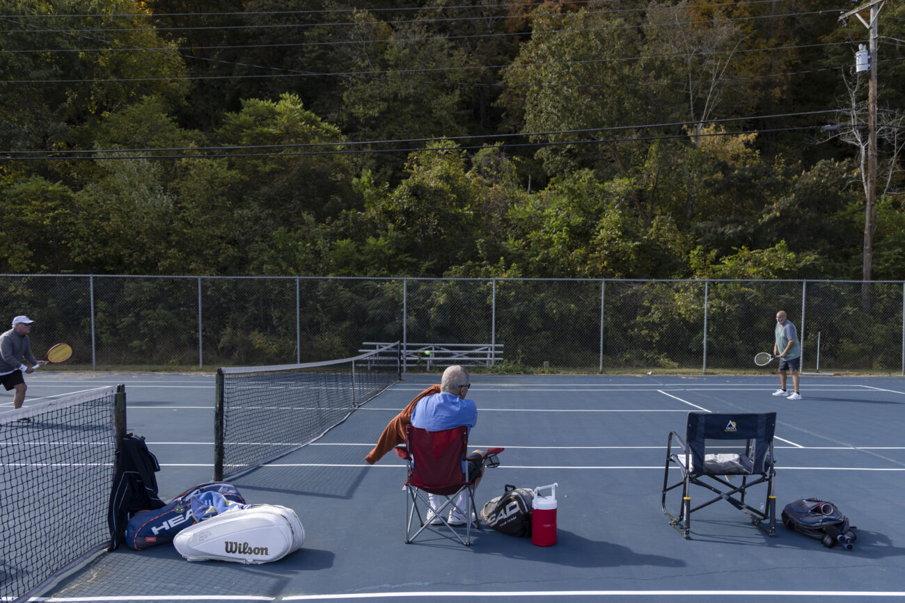 Earl Mayes puts on his jacket while watching County Judge Exec Huston Wells and Din Schierer play a round of tennis at the Panther Athletic Complex in Frankfort, Kentucky on Friday, Oct. 7, 2022. Photo by Martha McHaney.