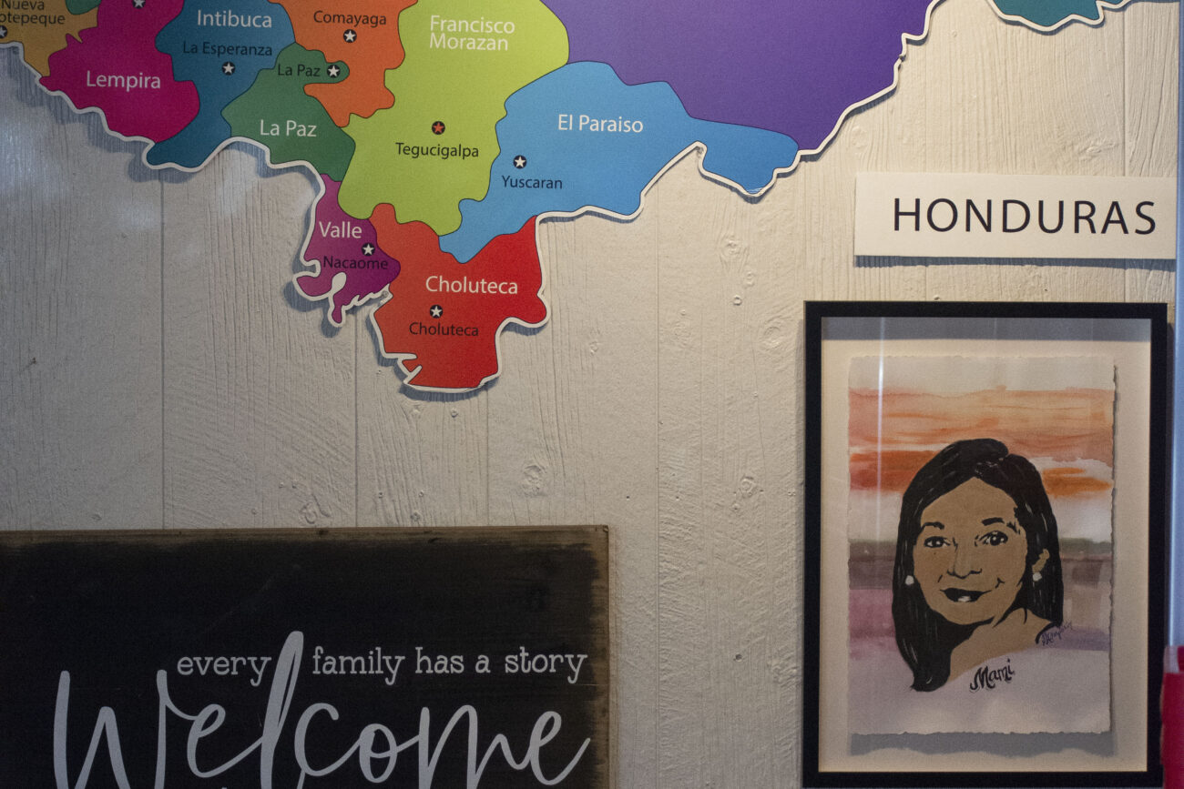 A map of Honduras details all 18 departments of the country at Mami Monchita’s in Frankfort, Kentucky., on Saturday, October 8, 2022. A table underneath it displays family members of the Hondura owner, Alda Diaz, as well as cultural items such as Honduran coffee. Photo | Nyah Leveretter