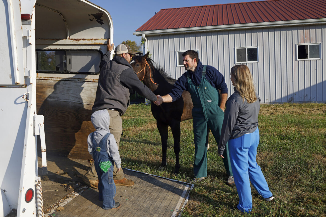 Dr. Josh Brown, second from right, greets Morgan Penn, second from left, before his horse Socks’ castration outside The Animal Clinic in Lawrenceburg, Kentucky, on Friday, October 7, 2022.
