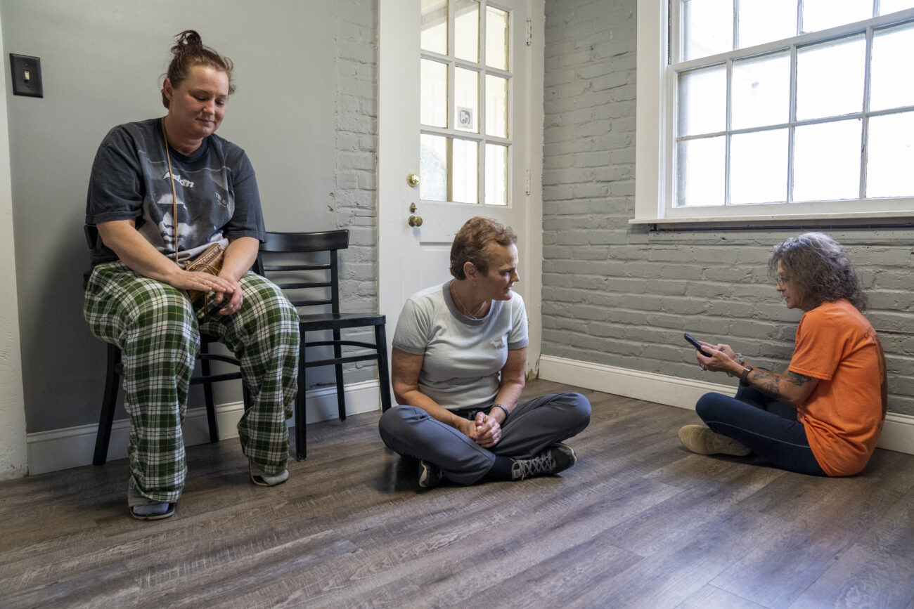 Jenny Hurst (middle) and friend Angela Cox (right) chat on the floor while waiting for veterinarian Dr. Scott Nieves to come and assess a client’s cat, and eventually get to Cox’s rescued bobcat she found on the side of the road. On Thursday, Oct. 6, 2022, brought it to Frankfort Veterinary Clinic to be assessed by the veterinarian and his veterinarian technicians in Frankfort, Ky. Photo by Carter Skaggs